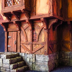Puede incluir: Una miniatura de edificio de madera con una puerta marr&oacute;n y una base de piedra. El edificio tiene una estructura de madera con vigas a la vista y una pared de ladrillo. El edificio est&aacute; pintado en tonos marrones y naranjas.