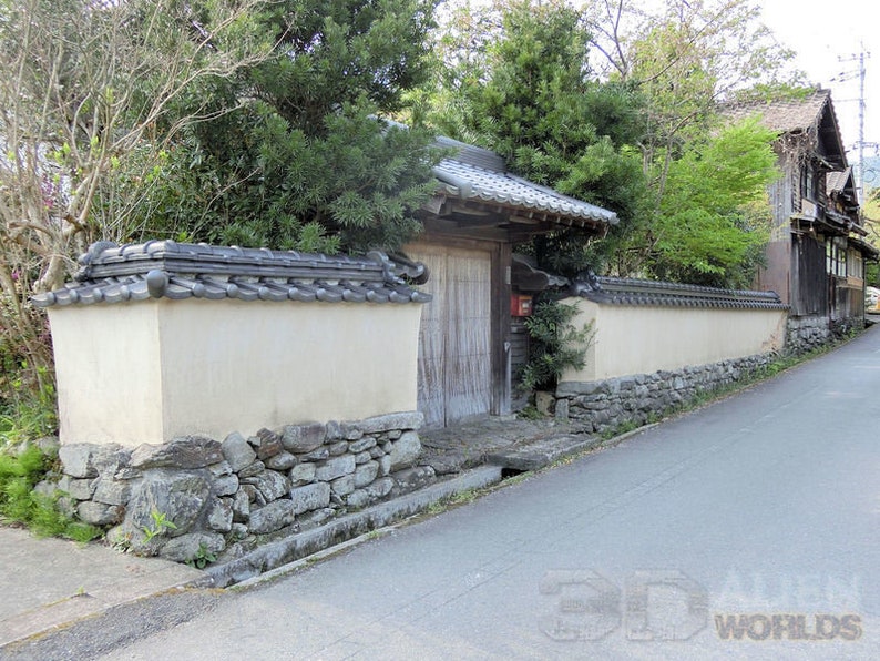 May include: A traditional Japanese style home with a stone wall and a wooden gate. The wall is made of stacked stones and is painted white. The gate is made of wood and has a dark brown finish. The gate is closed and has a small mailbox on the right side.