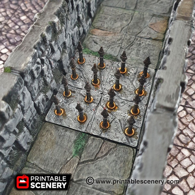 May include: A close-up of a 3D printed dungeon trap with a grid of metal spikes protruding from the floor. The spikes are painted a dark grey color and are surrounded by a light grey stone floor. The trap is designed for use in tabletop role-playing games.