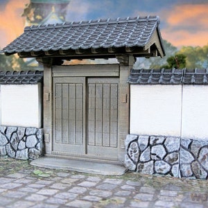 May include: A miniature Japanese-style gate with a gray tiled roof and wooden doors. The gate is set into a white wall with a stone base.