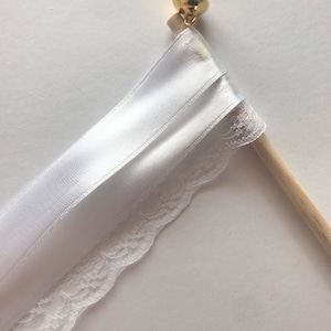 May include: White satin ribbon and lace wedding ceremony ribbon wand with a gold bell at the top.