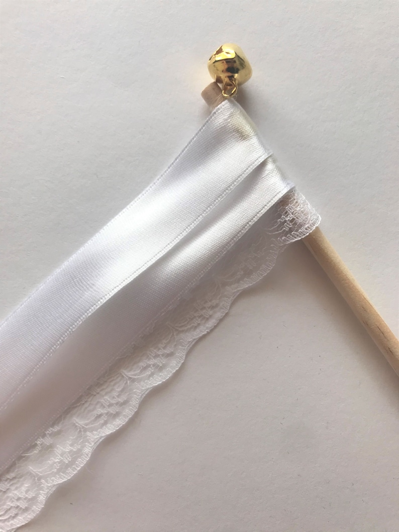 May include: White satin ribbon and lace wedding ceremony ribbon wand with a gold bell at the top.