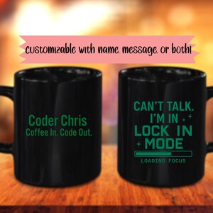 Puede incluir: Dos tazas de café negras con texto blanco. Una taza dice "Coder Chris Coffee In. Code Out." La otra dice "Can't Talk. I'm In Lock In Mode Loading Focus." Una pancarta rosa dice "personalizable con nombre, mensaje, o ambos!"