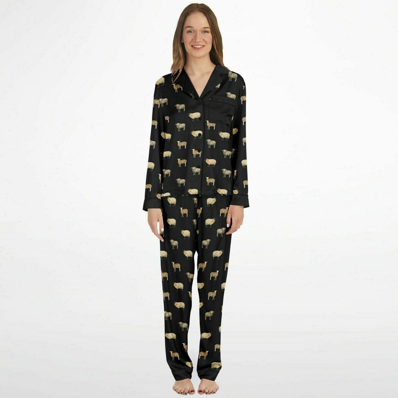 以下が含まれることがあります： 白い羊のプリントが施された黒いパジャマセット。トップスは襟付きで長袖。パンツはストレートレッグです。