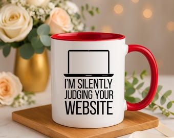 Puede incluir: Taza de cerámica blanca con borde y asa rojos. La taza presenta una silueta negra de un portátil con el texto "I'm silently judging your website".