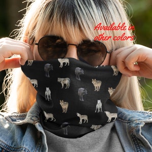 Puede incluir: Una máscara facial negra con un patrón repetido de lobos grises y blancos. El texto "Disponible en otros colores" es visible en la esquina superior derecha de la imagen.