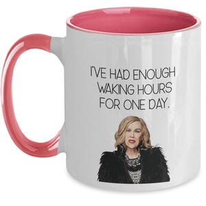 May include: White ceramic mug with a pink interior and handle. The mug features the text "I'VE HAD ENOUGH WAKING HOURS FOR ONE DAY." and an illustration of a woman with blonde hair and a black jacket.