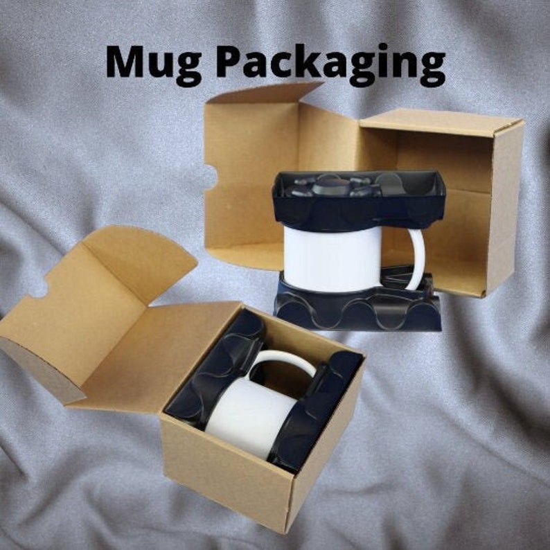 May include: Two white mugs in black protective holders inside open cardboard boxes. The boxes are brown and the text "Mug Packaging" is at the top of the image.