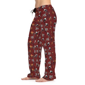 Op de afbeelding: Rode pyjamabroek met een patroon van kleurrijke lemuren. De broek heeft een trekkoord in de taille en een ontspannen pasvorm.