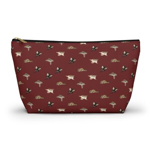 May include: A red zippered pouch with a repeating pattern of sugar gliders. The sugar gliders are in various poses, some are flying and some are perched.