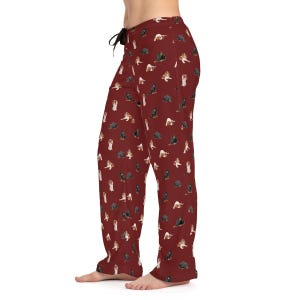 May include: Red pajama pants with a pattern of black and brown dogs. The pants have a drawstring waist and a relaxed fit.
