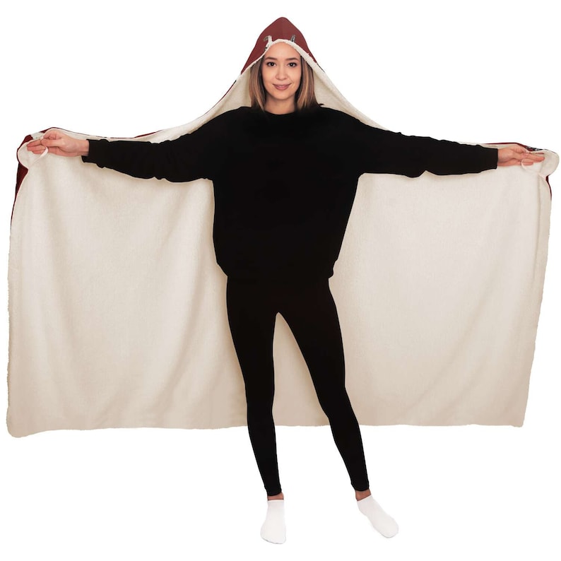 May include: A hooded blanket with a burgundy hood and a white fleece lining. The blanket is worn by a person standing with arms outstretched.