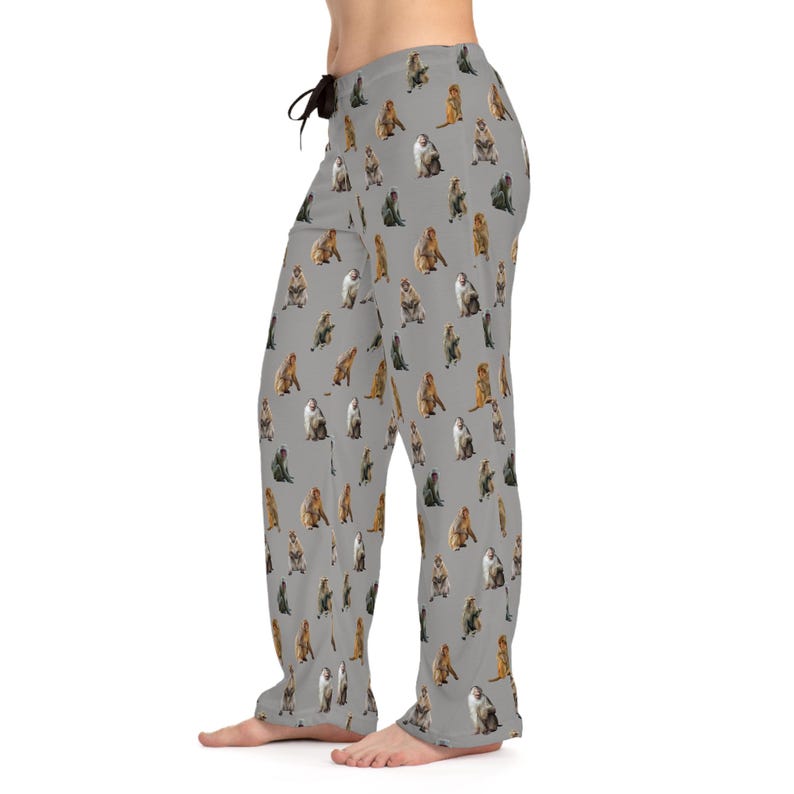 May include: Gray pajama pants featuring a repeating pattern of various monkey illustrations in shades of brown, gray, and white. The pants have a drawstring waist and a relaxed fit, suitable for lounging.