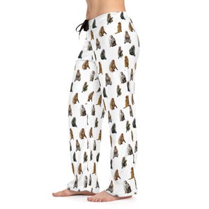 May include: White pajama pants featuring a repeating pattern of various monkey illustrations in shades of brown, gray, and tan. The pants have a drawstring waist and a relaxed fit, suitable for lounging or sleeping.