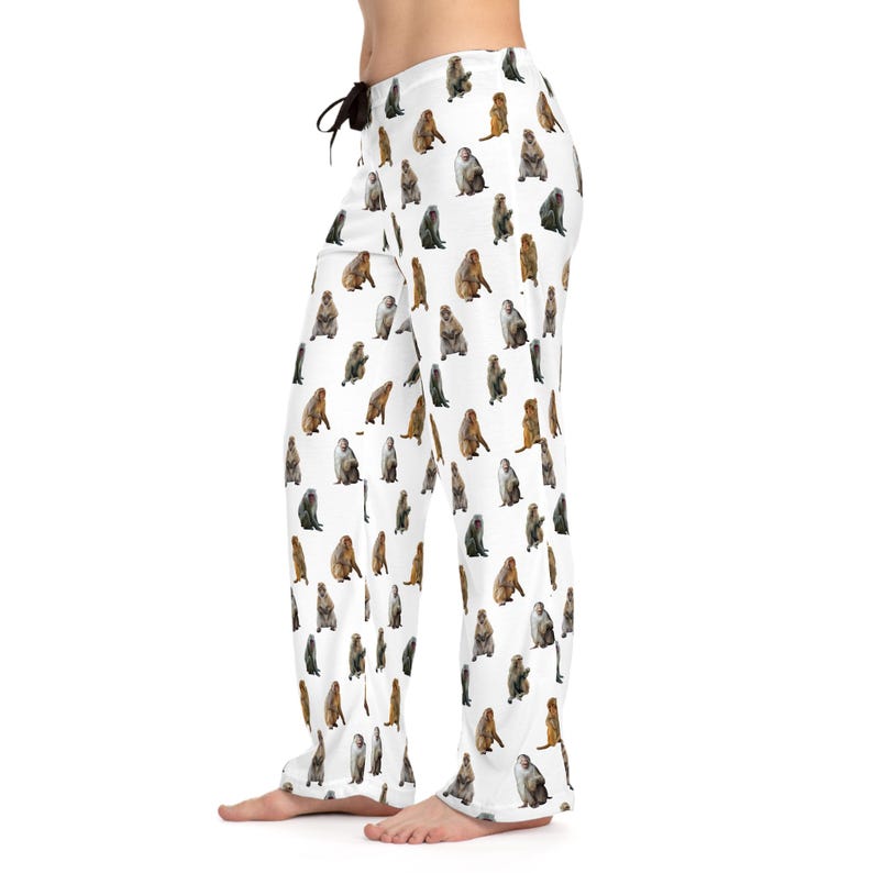 May include: White pajama pants featuring a repeating pattern of various monkey illustrations in shades of brown, gray, and tan. The pants have a drawstring waist and a relaxed fit, suitable for lounging or sleeping.
