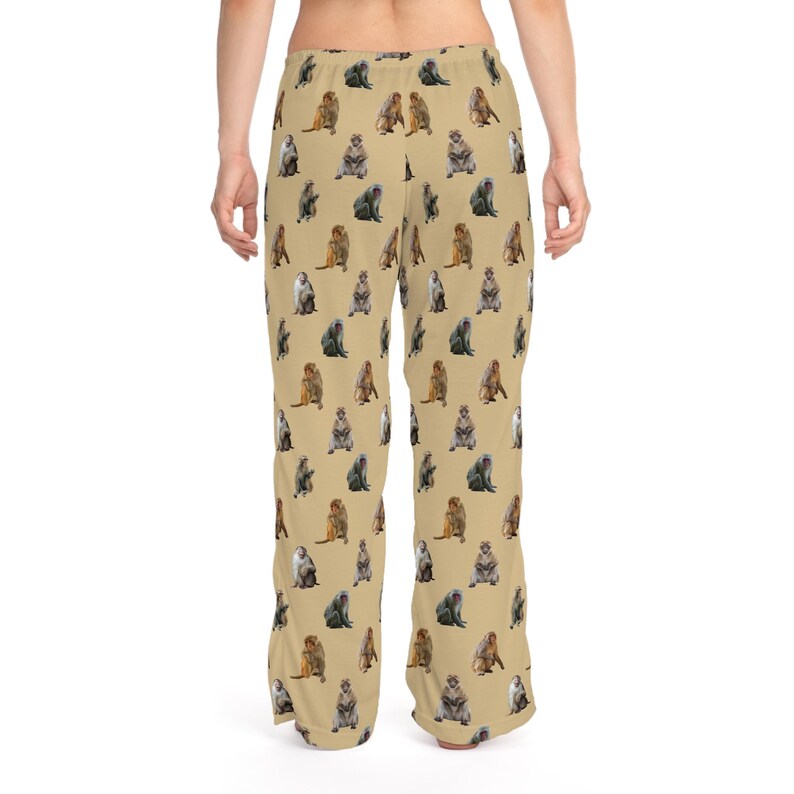 May include: Tan pajama pants with a repeating pattern of various monkey illustrations in shades of brown, gray, and tan. The pants are loose-fitting and made of a soft material.
