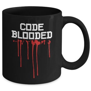 以下が含まれることがあります： 赤い塗料が垂れている白い文字で「CODE BLOODED」と書かれた黒いコーヒーカップ
