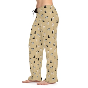 Könnte beinhalten: Beigefarbener Schlafanzug mit einem sich wiederholenden Muster aus schwarzen, braunen und weißen Hunden. Die Hunde sind alle in verschiedenen Posen, einige sitzen, einige stehen und einige laufen.