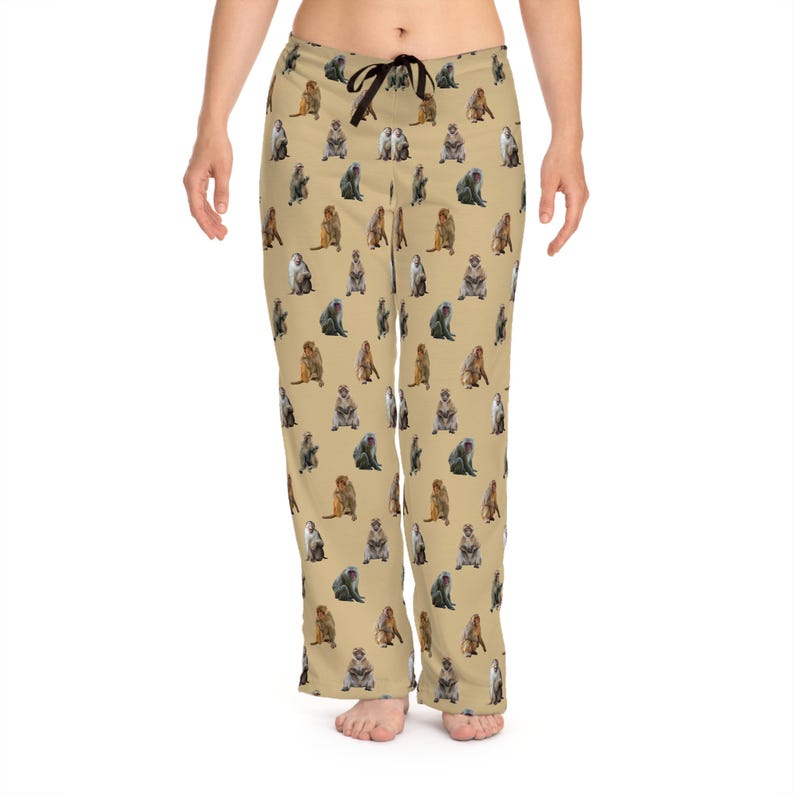 May include: Tan pajama pants with a repeating pattern of various monkey illustrations. The pants have a drawstring waist and a relaxed fit. The monkeys are depicted in shades of brown, gray, and tan.