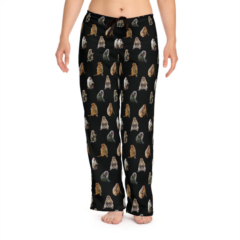 May include: Black pajama pants with a repeating pattern of various colored monkeys. The pants have a drawstring waist and a relaxed fit. The monkeys are in different poses and colors.