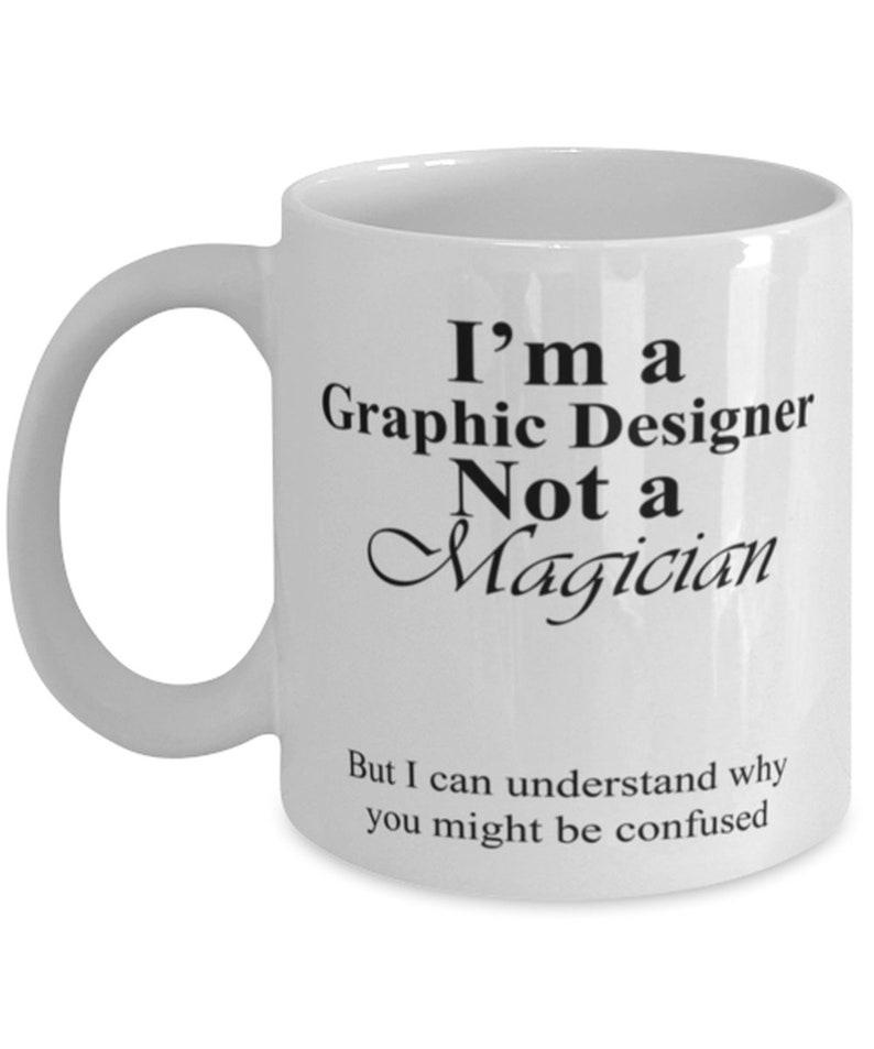 May include: White ceramic mug with a curved handle. The mug features black text that reads "I'm a Graphic Designer Not a Magician" and "But I can understand why you might be confused."