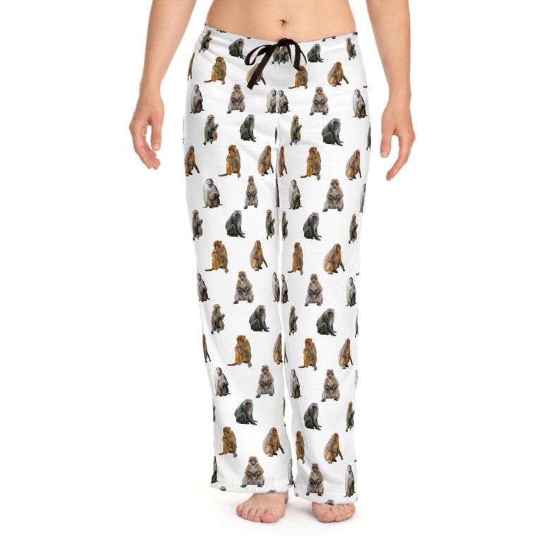 May include: White pajama pants featuring a repeating pattern of various monkey illustrations in shades of brown, gray, and tan. The pants have a black drawstring at the waist.
