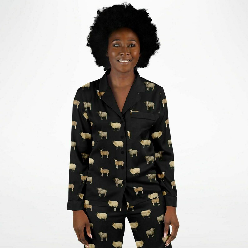 以下が含まれることがあります： 羊のプリントが施された黒いパジャマセット。トップスは襟付きで長袖。パンツはゴムウエストです。