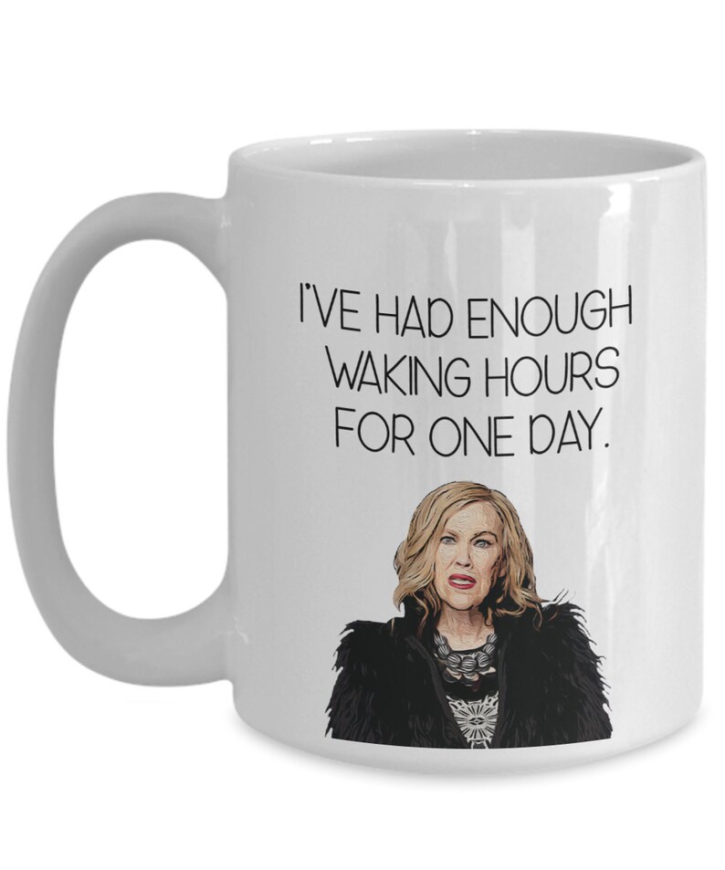 May include: White ceramic mug with a black handle featuring the text "I'VE HAD ENOUGH WAKING HOURS FOR ONE DAY." Below the text is a cartoon image of a woman with blonde hair wearing a black jacket.