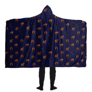 May include: A navy blue hooded blanket with a repeating pattern of brown and black Highland cattle. The blanket is large enough to cover a person from head to toe.