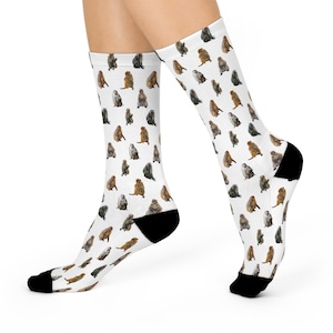 May include: White socks featuring a repeating pattern of monkey illustrations in brown, grey, and tan. The socks have black heels and toes.