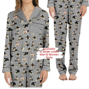 May include: Gray pajamas with a repeating pattern of Australian Shepherd dogs. The pajamas have a button-up top with a collar and long sleeves. The pants have an elastic waistband. The text "Available in other colors Men & Women Style" is visible on the image.