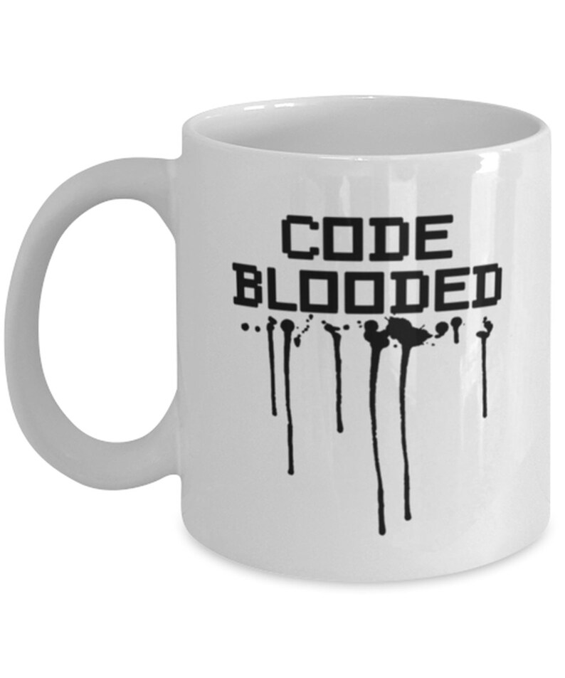以下が含まれることがあります： 白いセラミック製のコーヒーカップで、黒い文字で「CODE BLOODED」と書いてあります。ピクセル化されたフォントで書かれています。黒い塗料が文字から垂れています。