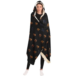 May include: A black hooded blanket with a white sherpa lining. The blanket features a repeating pattern of brown and black bulls.