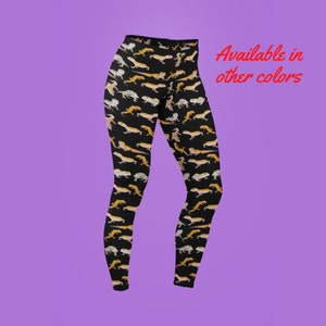Puede incluir: Leggings negros con un patrón repetido de geckos amarillos y naranjas. Disponible en otros colores.
