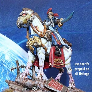 Puede incluir: Figura en miniatura de un guerrero montado en un caballo blanco, con armadura dorada y azul. El guerrero sostiene una espada, y el caballo tiene elementos mecánicos. La base incluye calaveras y un letrero.