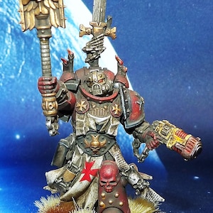 May include: A painted miniature figure of a warrior in red and cream armour with a red cross emblem. The figure holds a gold-coloured staff topped with an eagle and skull icon in one hand and a metallic pistol in the other, featuring skull details.