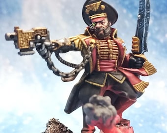 Pode incluir: Uma figura miniatura pintada de um soldado vestindo um uniforme vermelho e dourado, um chapéu preto com um emblema de águia dourada, e segurando uma arma e uma espada. A figura está em pé sobre uma base rochosa com efeitos de fumaça e fogo.