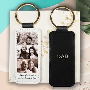 May include: Two leather keyrings with gold rings. One keyring has a white background with three photos of a family and the text "Time flies when we're having fun". The other keyring is black with the word "DAD" in gold lettering.