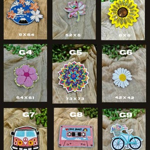 May include: A collection of embroidered patches featuring various designs. Includes a blue patch with a mountain and floral design, a pink lotus flower, a yellow sunflower, a pink flower, a colorful mandala, a white daisy, a van, a cassette tape, and a bicycle.