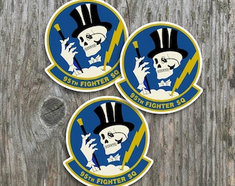 May include: Three circular stickers featuring a skeleton wearing a black top hat and monocle, holding a cane. The design includes a yellow lightning bolt on a blue background with the text 95TH FIGHTER SQ in yellow lettering.