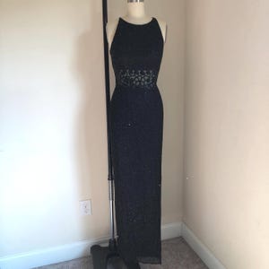 May include: A black sequined sleeveless gown with a sheer lace panel at the waist.