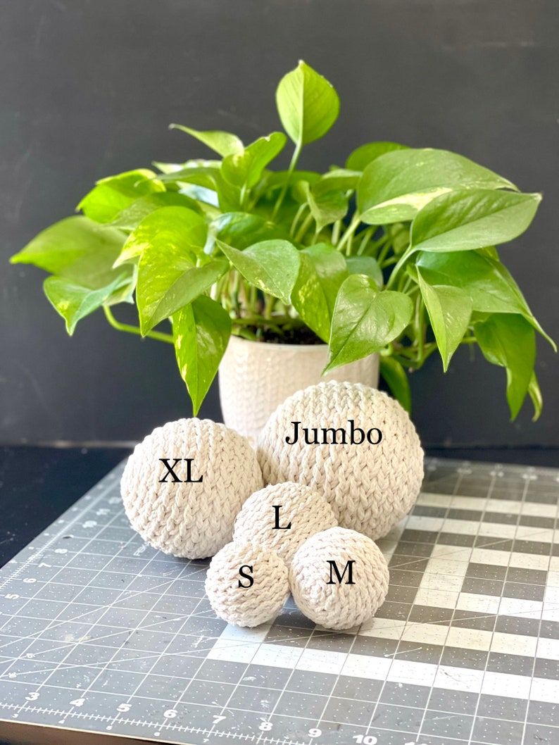 May include: Five white crocheted balls of different sizes, labeled "Jumbo", "XL", "L", "M", and "S".