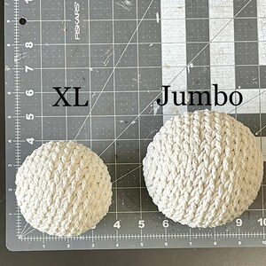 May include: Two white crocheted balls, one labeled "XL" and the other "Jumbo".