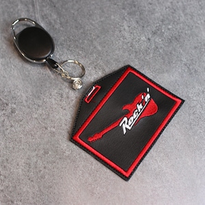 May include: Black leather key chain with a red embroidered guitar and the text "Rock'n'" on it.