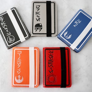 Puede incluir: Cinco cuadernos de cuero de diferentes colores con diseños de Star Wars y texto en japonés. Los cuadernos tienen un cierre de banda elástica blanca.