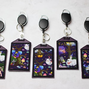 Può includere: Cinque porta badge retrattili viola e neri con diverse immagini di cartoni animati di fantasmi e altri personaggi spettrali. Ogni porta badge ha un rotolo retrattile nero e un anello di metallo argentato.