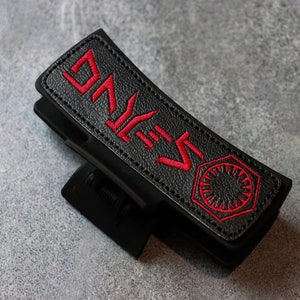 May include: Black leather phone case with a red embroidered "S-KYWALKER" and the First Order symbol.