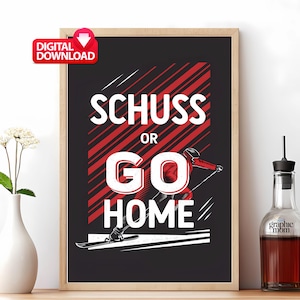 May include: Framed digital print with the text "SCHUSS OR GO HOME" in white and red. The artwork features a skier in red and black against a black background with red diagonal stripes. A "DIGITAL DOWNLOAD" sticker is in the upper left corner.