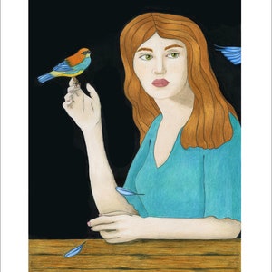 May include: A woman with long red hair sits at a table with a small blue and orange bird perched on her finger. The background is black and there are blue feathers scattered on the table.