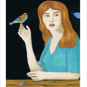 May include: A woman with long, red hair sits at a wooden table. She is wearing a teal blue dress and holding a small, colorful bird in her hand. There are blue feathers scattered on the table.